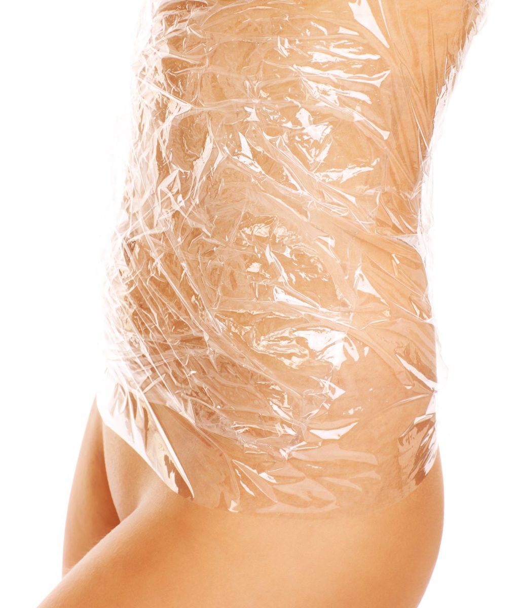 A picture of female belly wraped with foil over white background