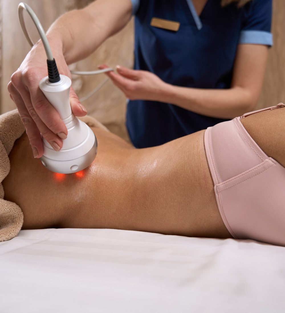 Specialist performing an RF lifting procedure on African American woman in the area of the buttocks in spa salon